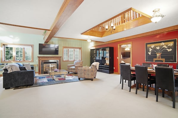 A spacious living room with a fireplace, a dining area, and a staircase.