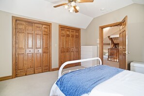 A bedroom with a bed, wooden wardrobe, and a ceiling fan.