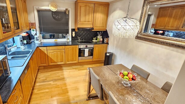A kitchen with wooden cabinets, a black countertop, a sink, and a dining table with a fruit bowl. - Spacious Bergen House With Stunning Mountain Views (Bergen)