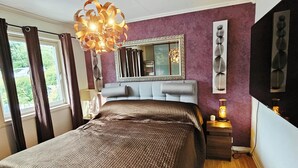 A bedroom with a large bed, a mirror, a nightstand with a lamp, and a view of the outdoors through the window. - Spacious Bergen House With Stunning Mountain Views (Bergen)