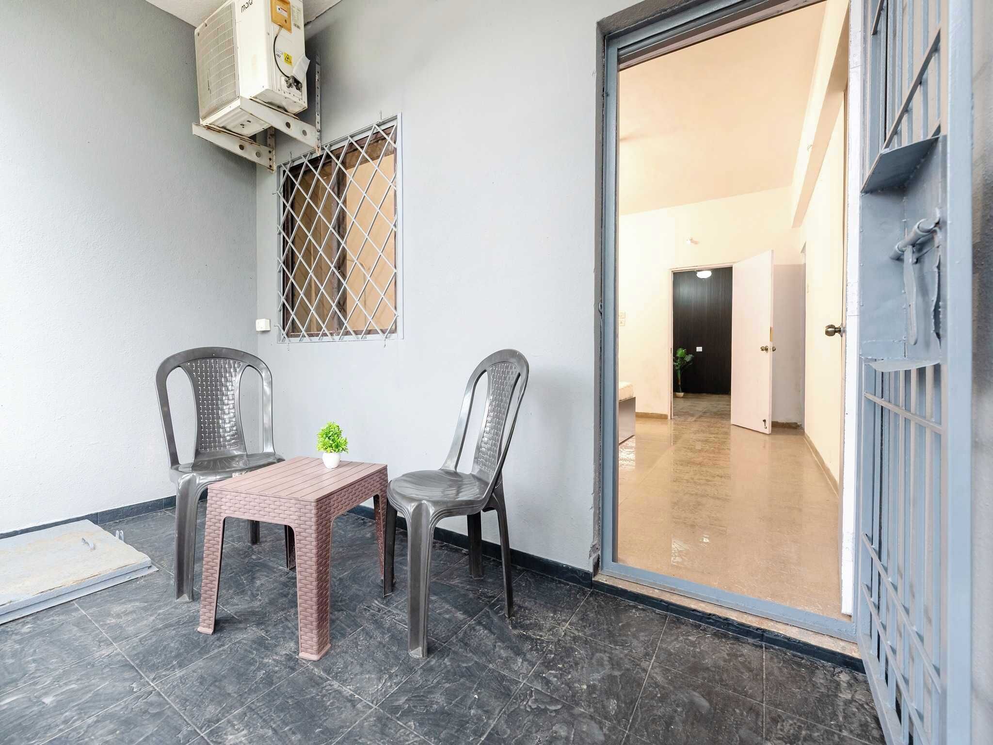 A room with two chairs, a small table, and an air conditioning unit mounted on the wall.