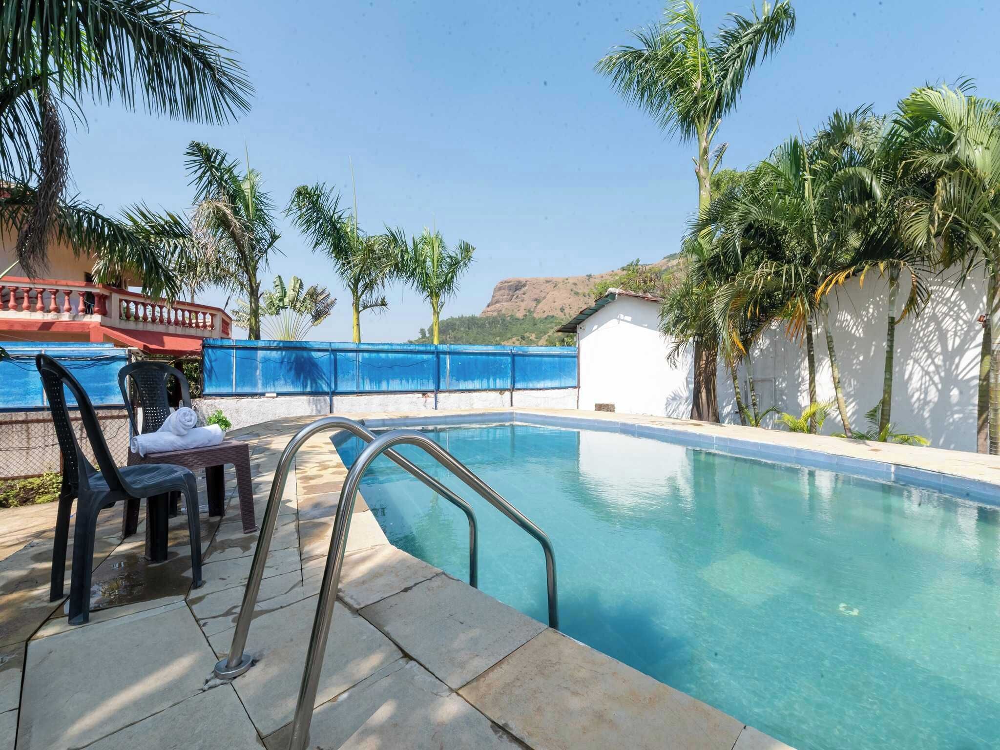 Une piscine à l’eau d’un bleu cristallin, entourée de palmiers et bordée d’un bâtiment blanc.