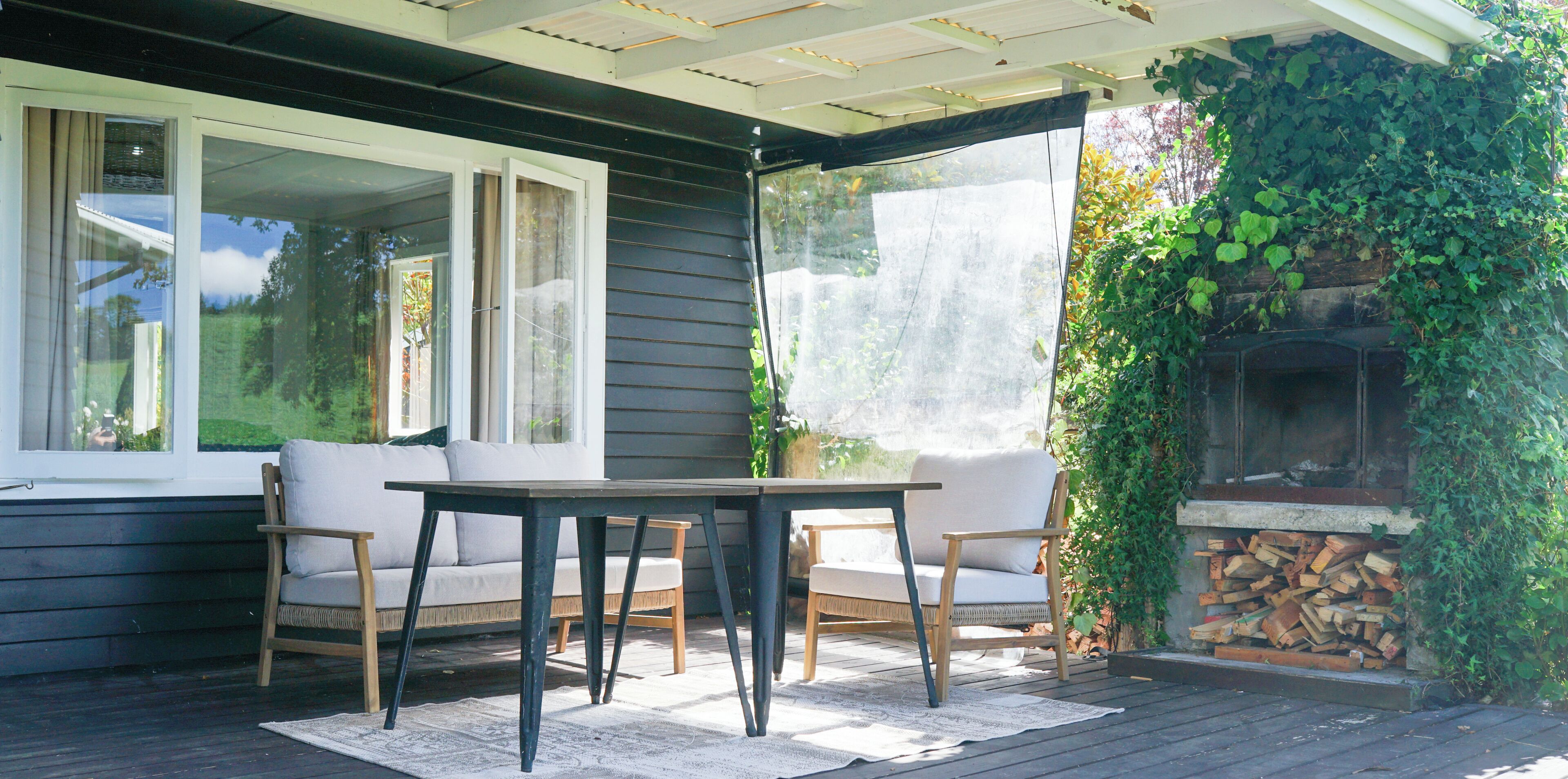 Un patio techado con mesa y sillas, una chimenea y vistas al exterior.