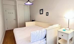 A bedroom with a bed, a nightstand, a lamp, and a door. - MyStay - Moura Lighthouse (Vilamoura)