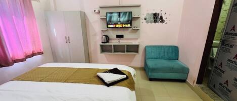 Une chambre d’hôtel comprenant un lit, une télévision, une armoire et un coin salon.