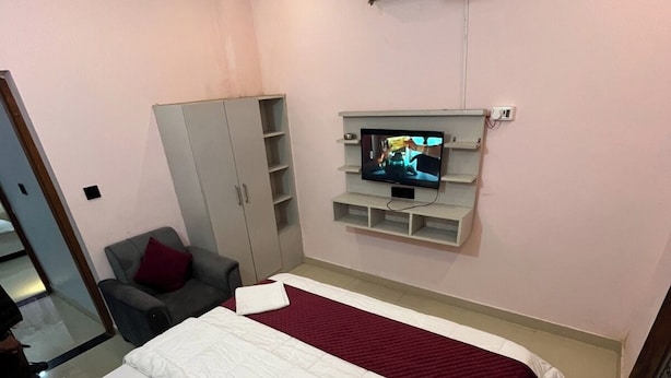 A bedroom with a bed, a TV, a wardrobe, and a ceiling fan.