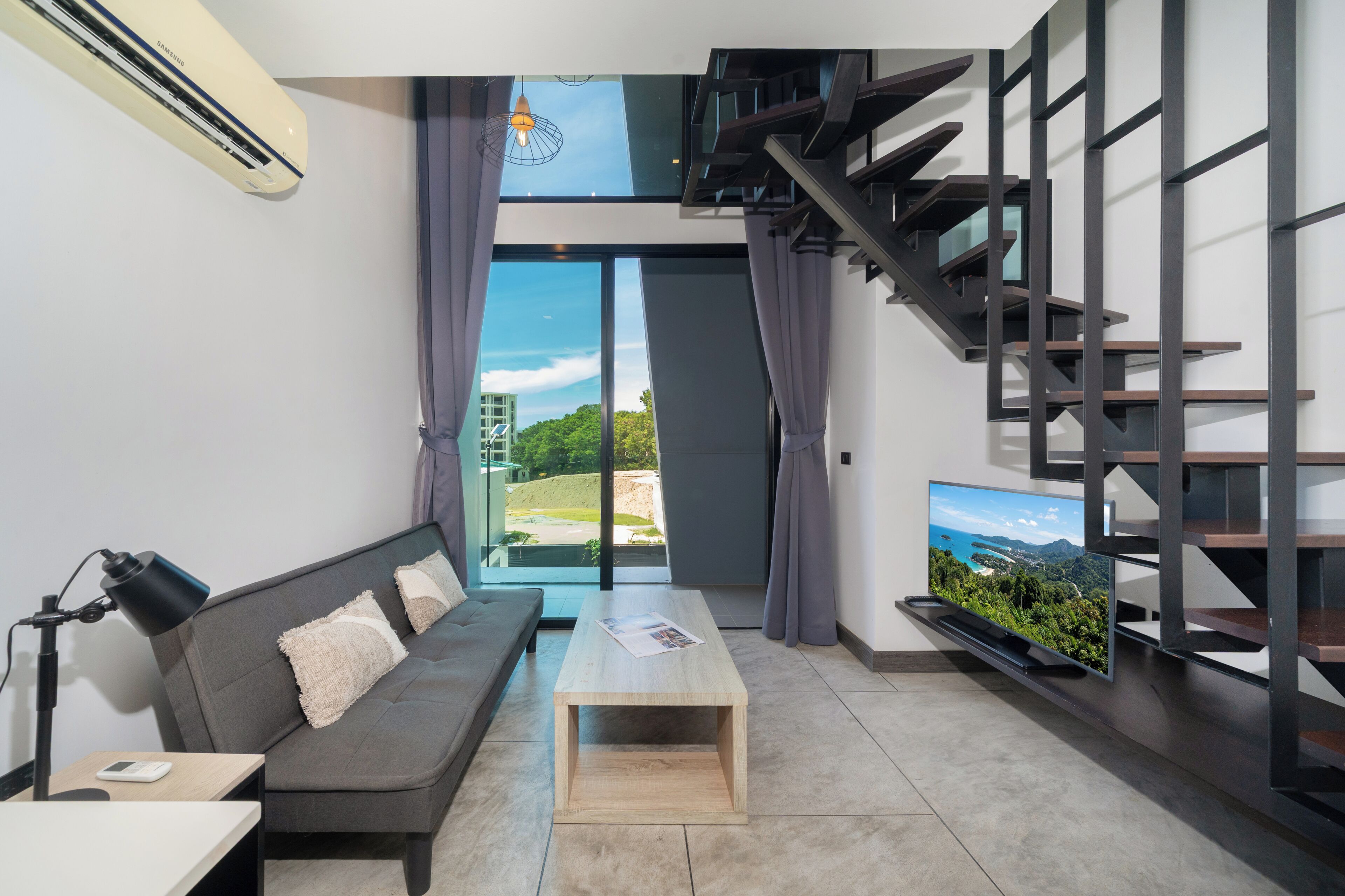 Una sala de estar moderna con sofá, mesa de centro, televisor y una escalera.