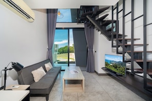 Una sala de estar moderna con sofá, mesa de centro, televisor y una escalera.