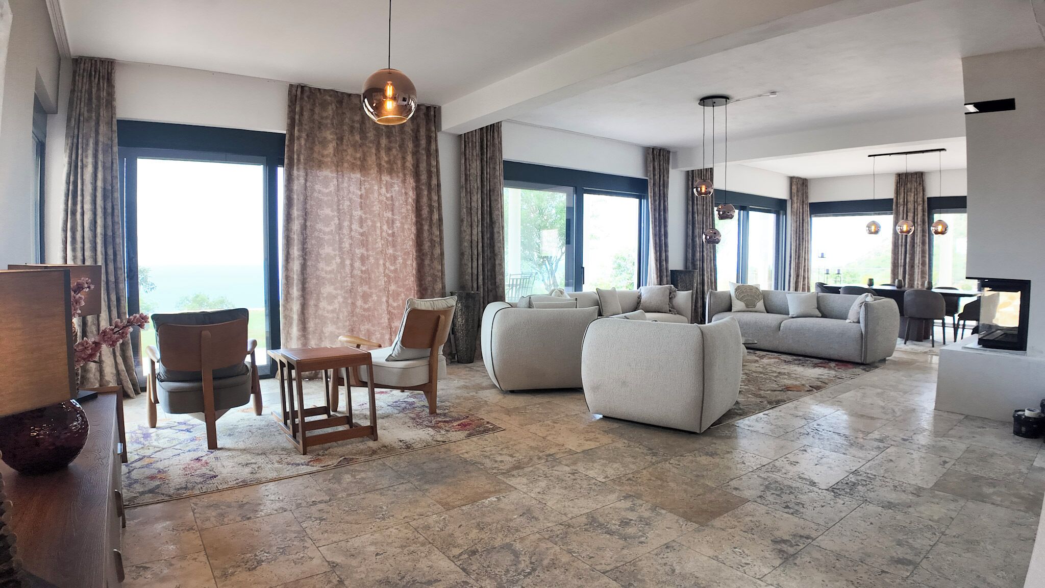 A spacious living room with a large sofa set, a dining area with a table and chairs, and a television.