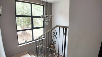 A staircase with a wrought iron railing and a large window with a view of greenery.