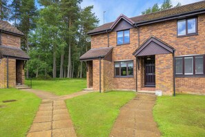 A two-story brick house with a paved driveway, a satellite dish, and a well-maintained lawn.