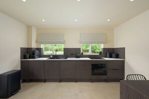 A modern kitchen with dark wood cabinets, a built-in oven, and a window with a view of greenery.