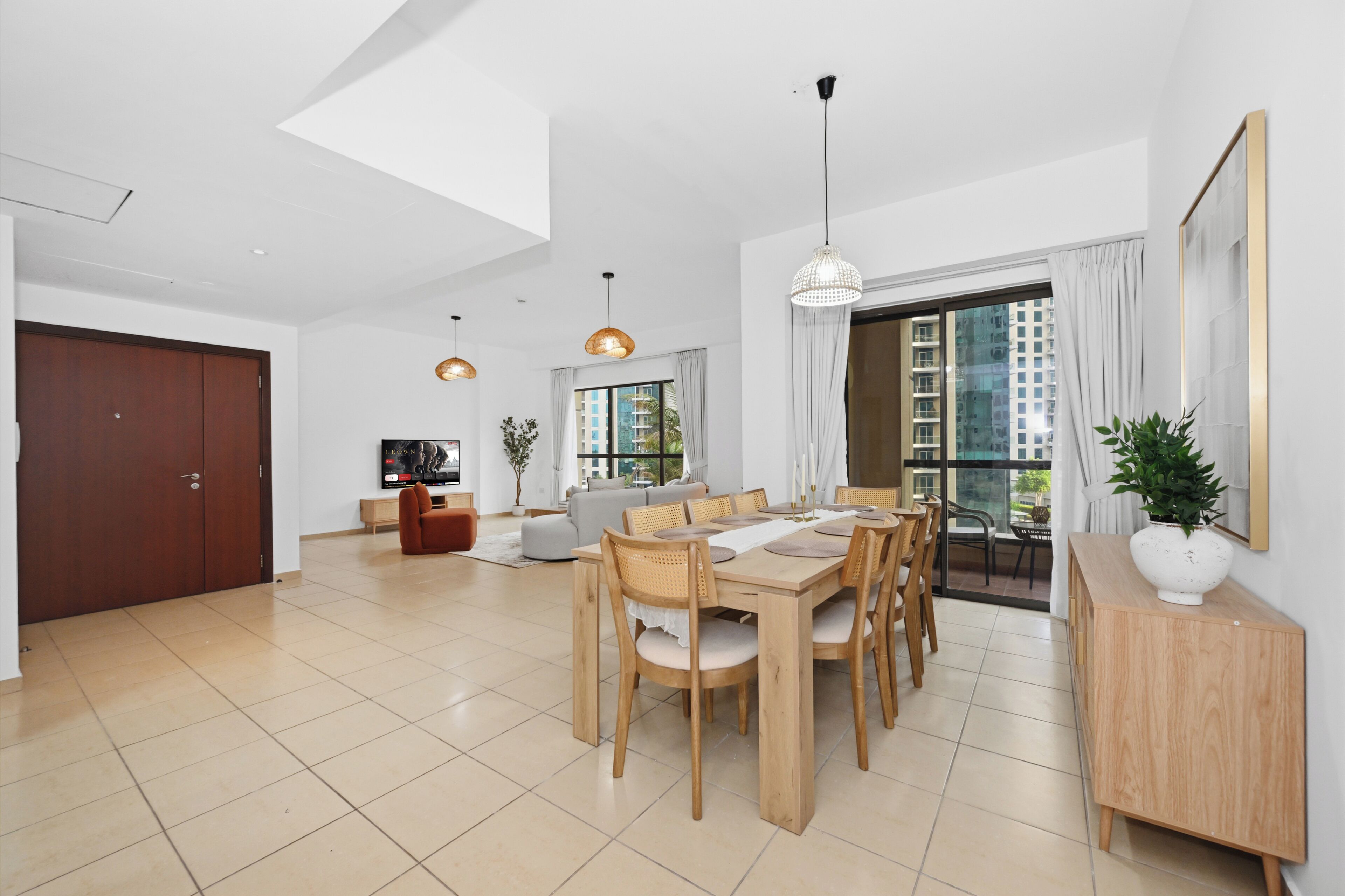 Uma sala de estar ampla com uma mesa de jantar, cadeiras, um sofá e uma televisão.