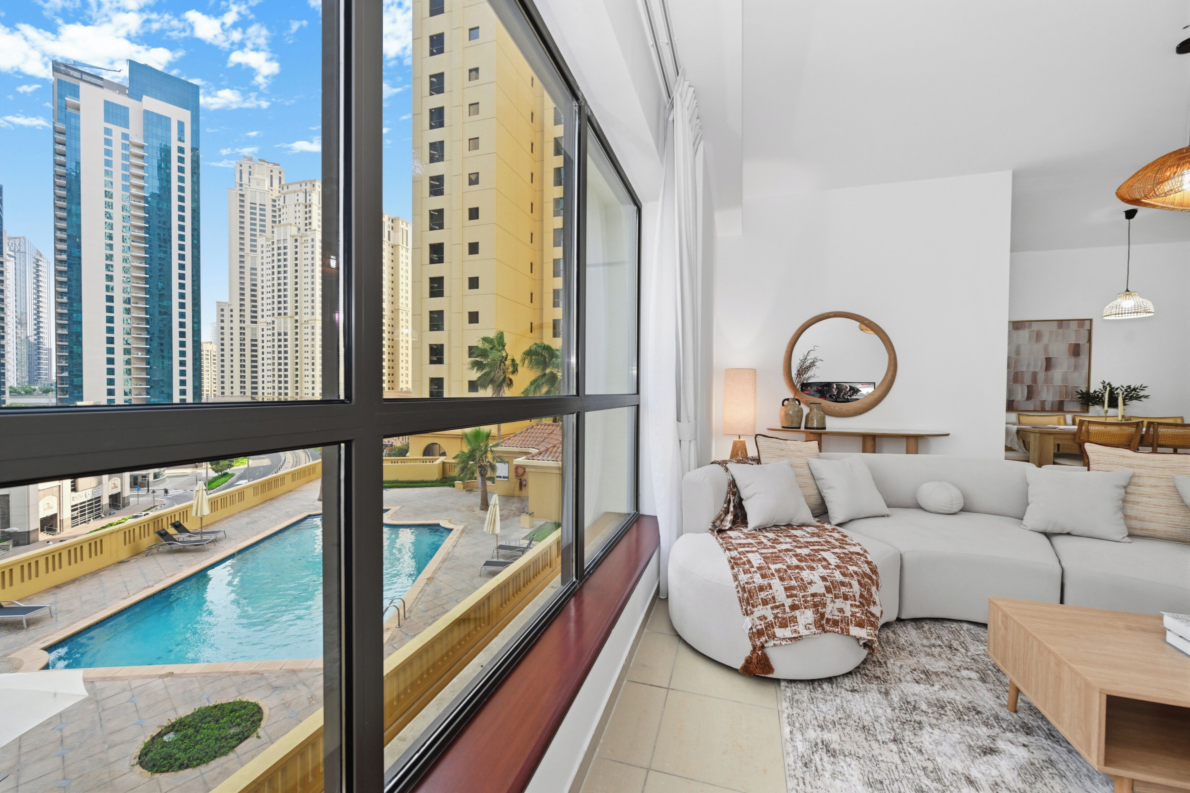 Uma sala de estar moderna com uma grande janela que dá para uma piscina e edifícios altos.