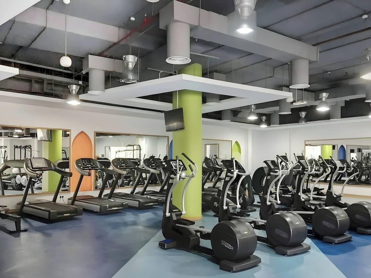 A gym with multiple treadmills, weight machines, and a blue floor.