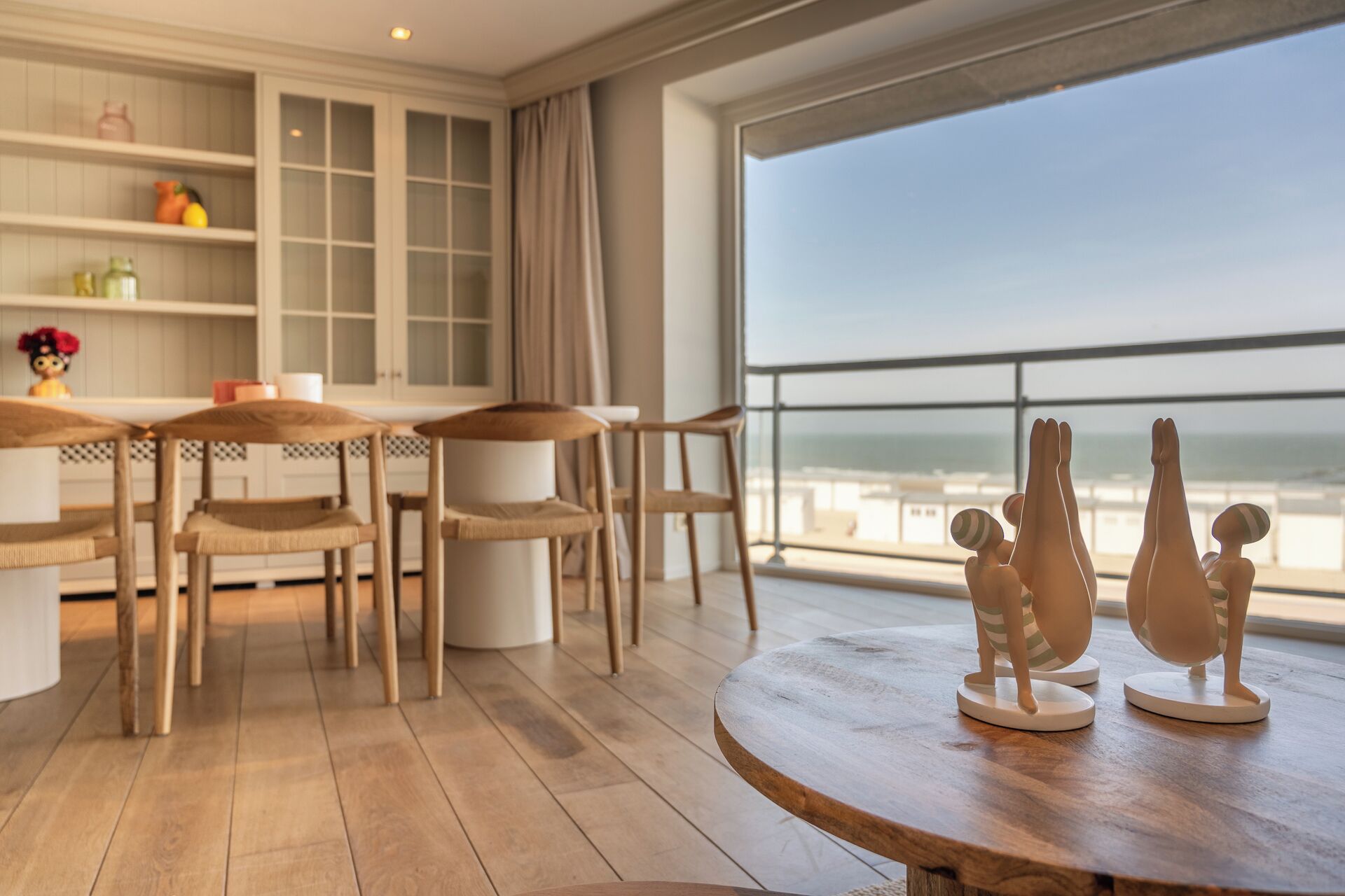 A dining area with a view of the sea, wooden furniture, and decorative items on a table.