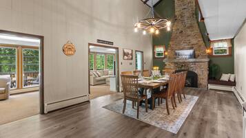 A spacious dining area with a stone fireplace, wooden dining table, and chairs.