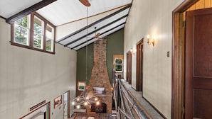 A staircase with a wooden handrail, a stone fireplace, and a dining area with a table set for four. - Lakefront Retreat,Sleeps 8, Kayaks & Fishing (Pine Grove)
