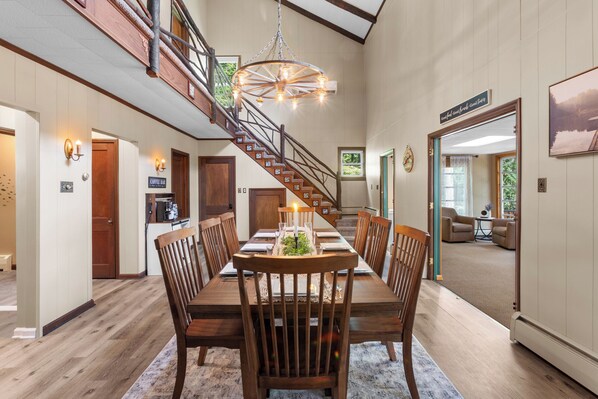 A spacious dining area with a high ceiling, a staircase with a wooden railing, and a coffee bar. - Lakefront Retreat,Sleeps 8, Kayaks & Fishing (Pine Grove)