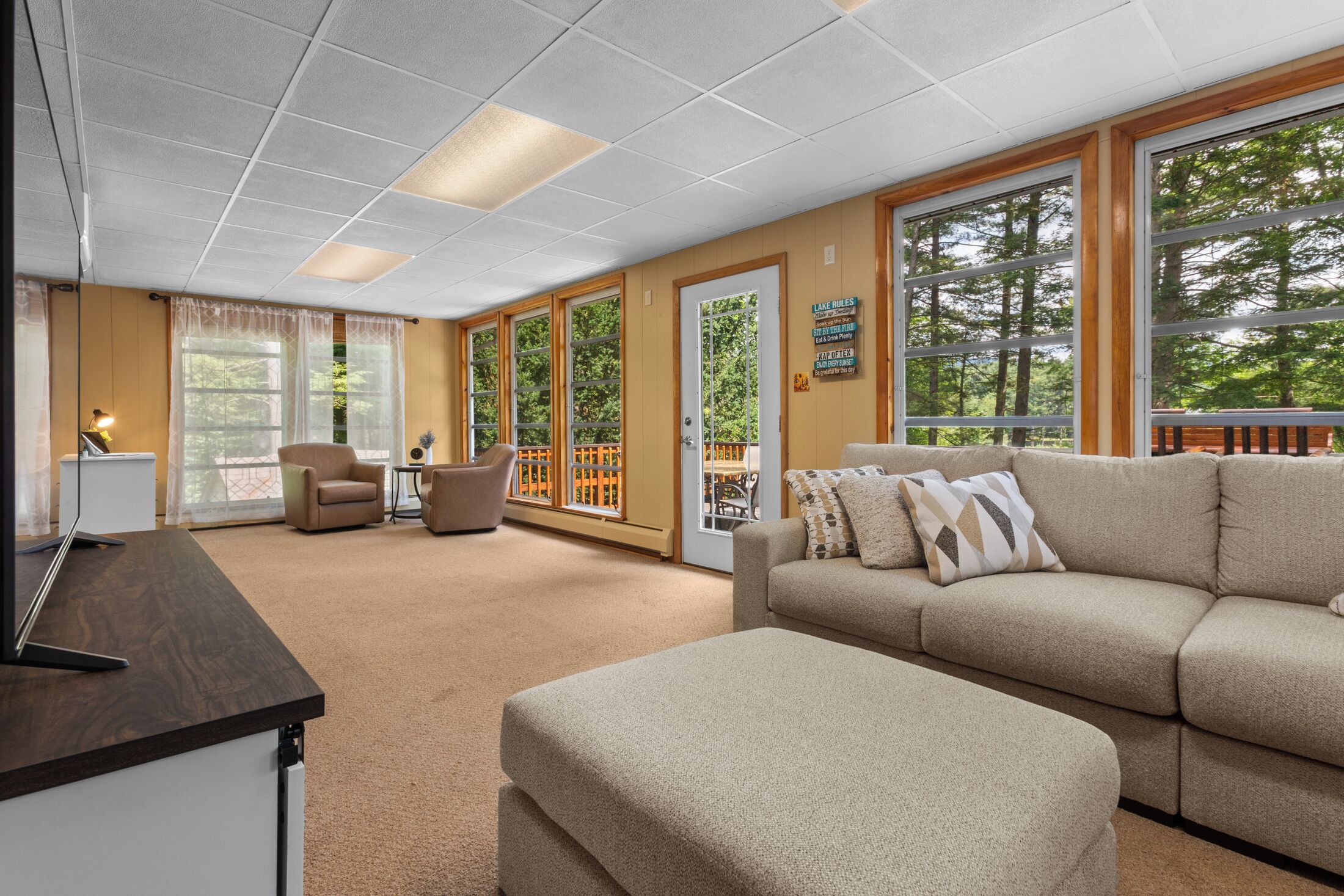 A spacious living area with a large window, a sofa, a chair, and a desk.