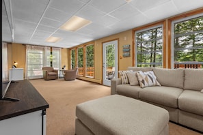 A spacious living area with a large window, a sofa, a chair, and a desk. - Lakefront Retreat,Sleeps 8, Kayaks & Fishing (Pine Grove)