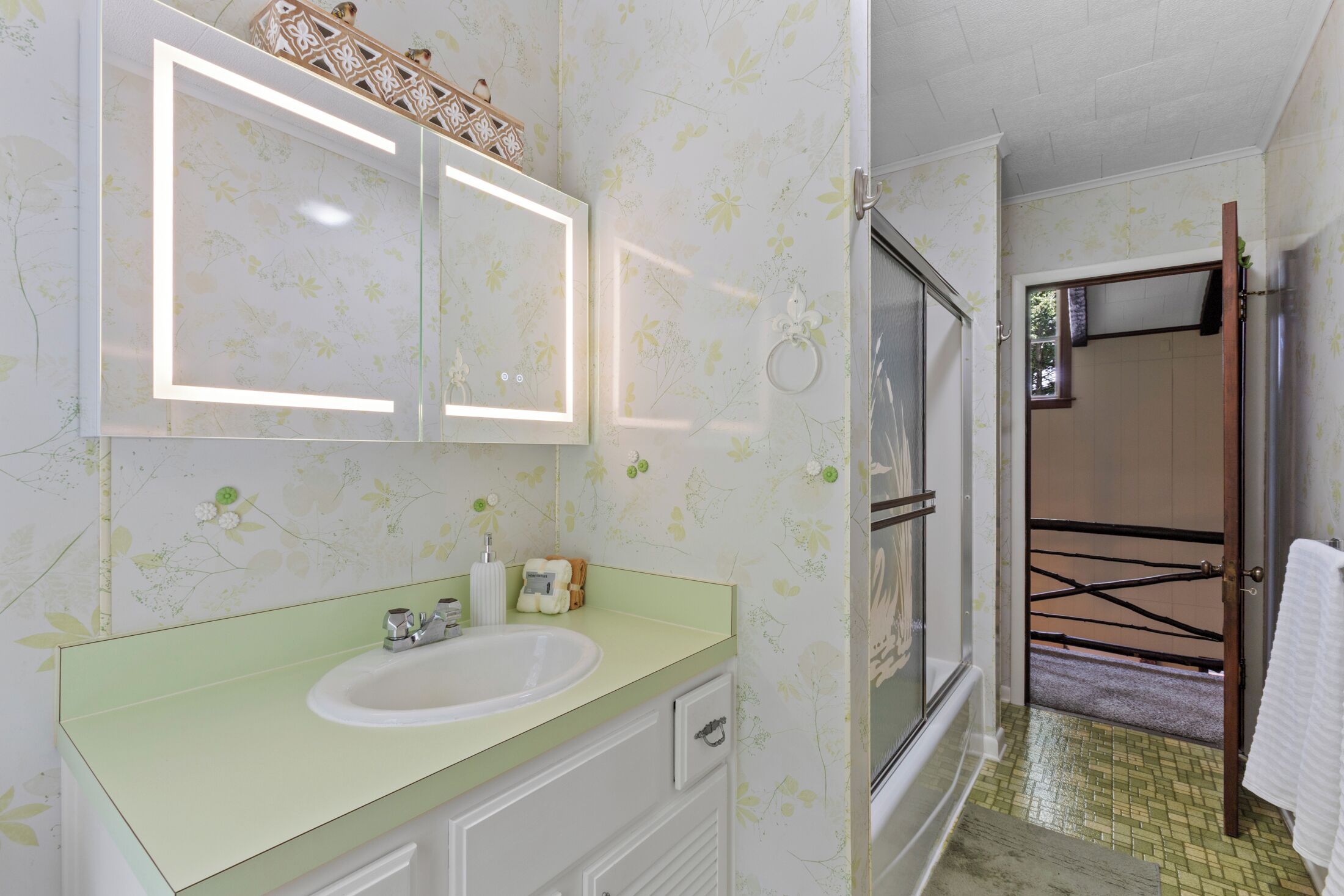 A bathroom with a sink, mirror, and shower.