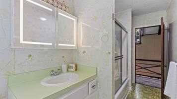 A bathroom with a sink, mirror, and shower.
