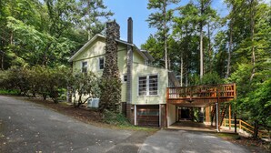 A two-story house with a garage, a wooden deck, and a staircase leading to a covered porch. - Lakefront Retreat,Sleeps 8, Kayaks & Fishing (Pine Grove)