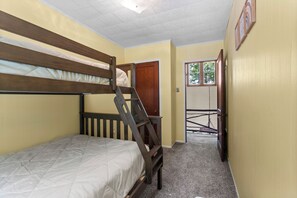 A bunk bed room with a wooden ladder, a door leading to a balcony, and a small window.
