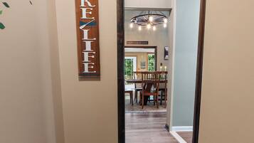 A hallway with a wooden sign reading 'LAKEFIELF' on the wall, leading to a dining area with a chandelier and wooden furniture.
