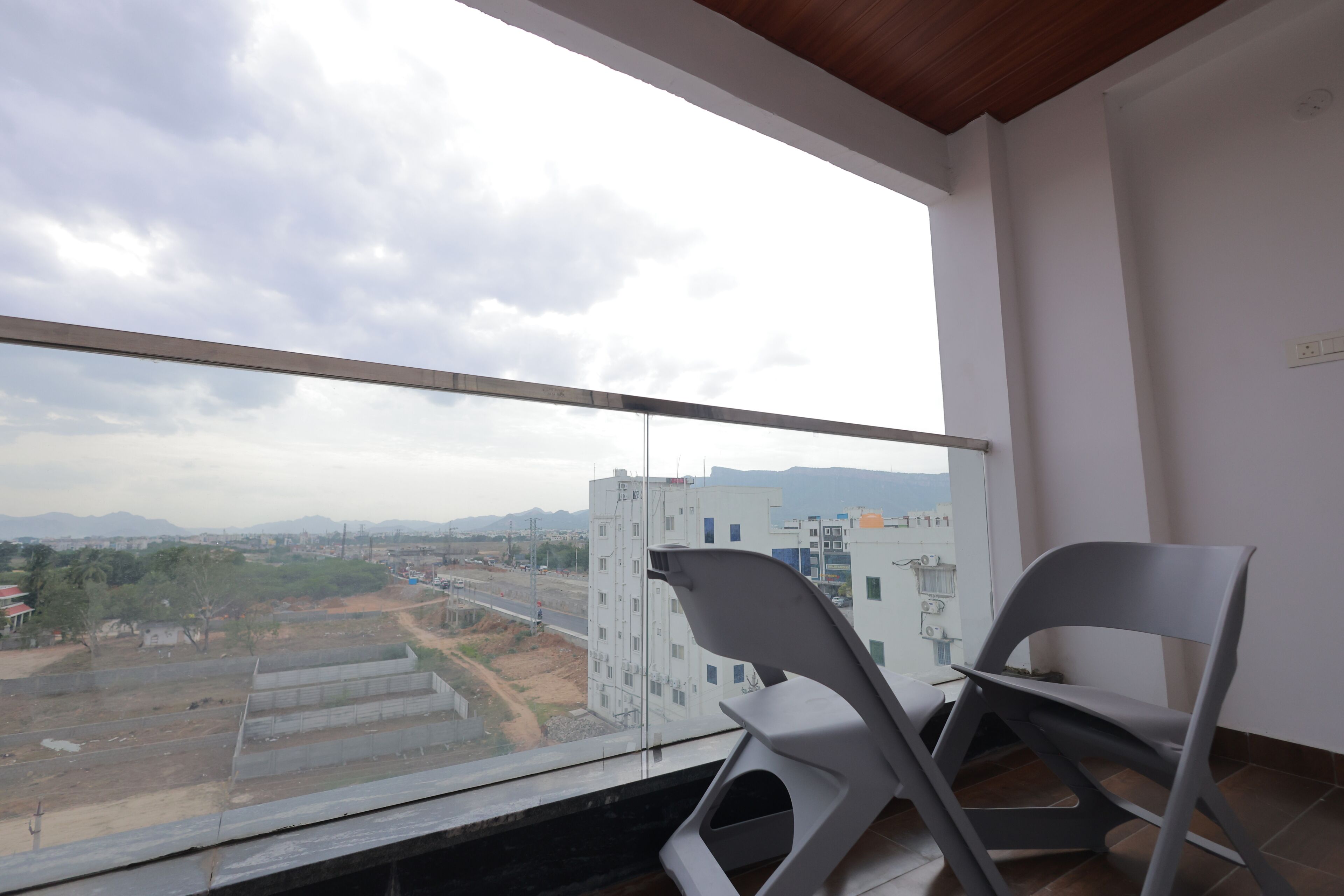 Un balcón con vistas a un paisaje urbano, una silla y un alféizar.
