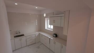 Una cocina con armarios blancos, un lavabo y un ventanal.