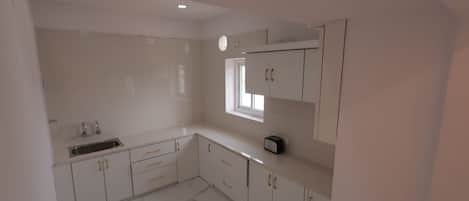 A kitchen with white cabinets, a sink, and a window.