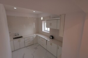 Una cocina con armarios blancos, un lavabo y un ventanal.