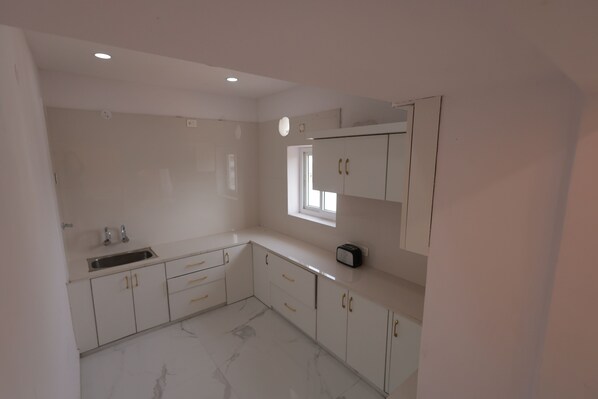A kitchen with white cabinets, a sink, and a window.
