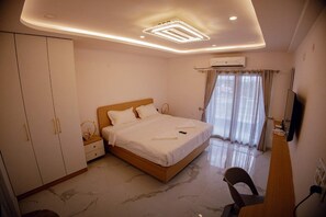 A bedroom with a bed, wardrobe, TV, and an air conditioning unit.