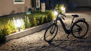 Een fiets geparkeerd voor een gebouw met een grindpad en een verlichte tuin.