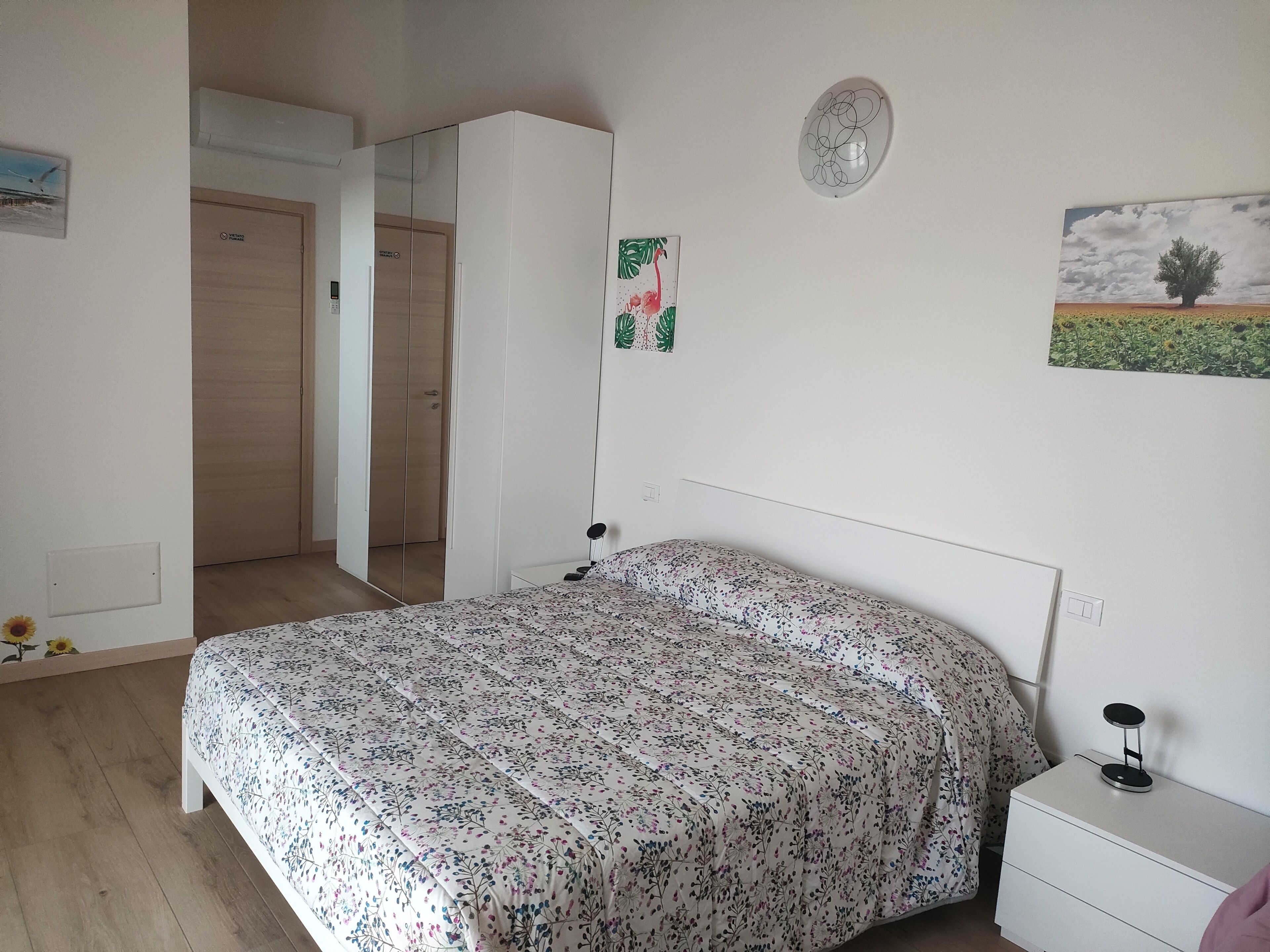 Ein Schlafzimmer mit Bett, Nachttisch, Kleiderschrank und einer Tür zu einem anderen Raum.