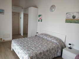 Un dormitorio con cama, mesita de noche, armario y una puerta que da a otra habitación.