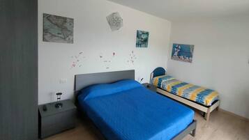 Une chambre à coucher avec un grand lit, un plus petit lit, une table de chevet et un mur décoré d’œuvres d’art.