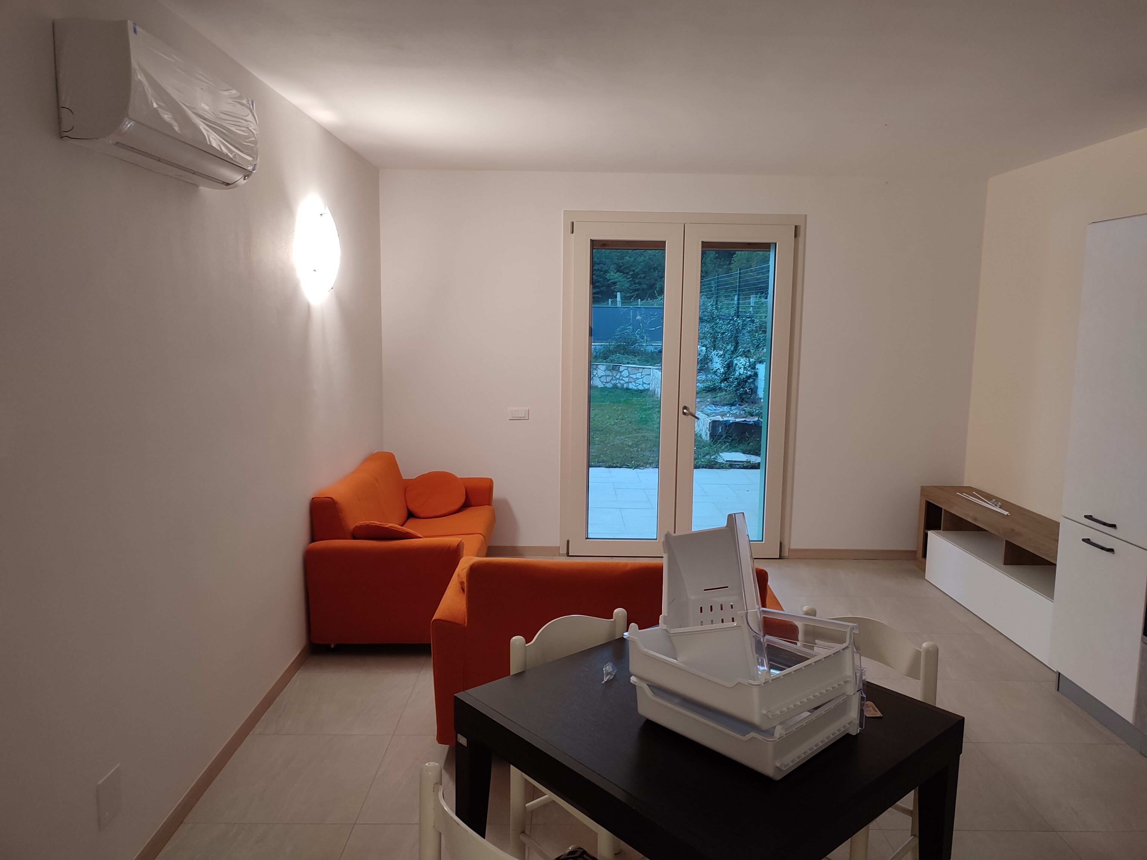 Um espaço compacto para viver, com sofá, mesa de jantar e área de kitchenette.