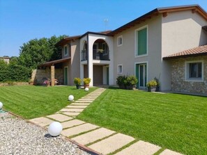 A two-story house with a balcony, a stone facade, and a well-maintained lawn. - Corte del Sole (Valeggio sul Mincio)