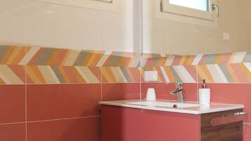 Un baño con tocador rojo, espejo y salpicadero con estampado en zigzag.