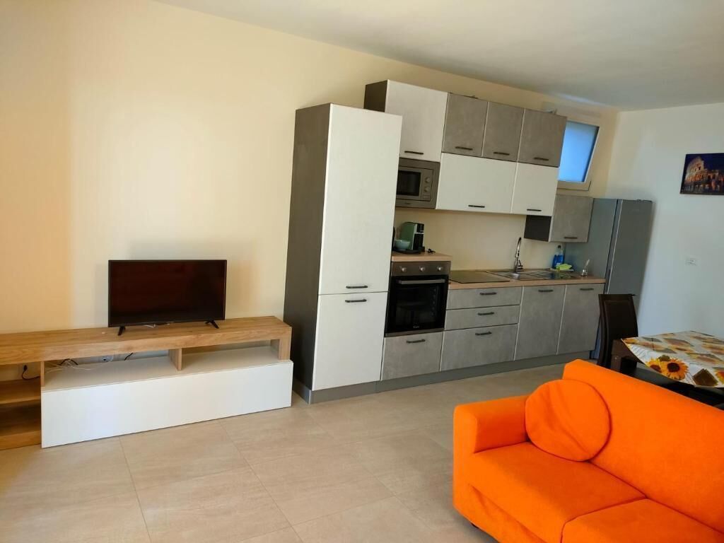 Une cuisine moderne dotée d’appareils électroménagers intégrés, un coin repas avec un banc et un canapé orange.