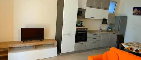 Eine moderne Küche mit integrierten Geräten, ein Essbereich mit einer Bank und ein orangefarbenes Sofa.