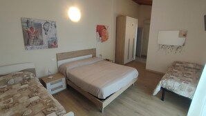 Een slaapkamer met een bed, nachtkastje, kledingkast en een kleine tafel.