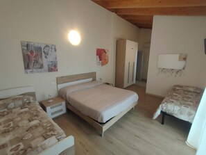Un dormitorio con cama, mesita de noche, armario y una pequeña mesa.