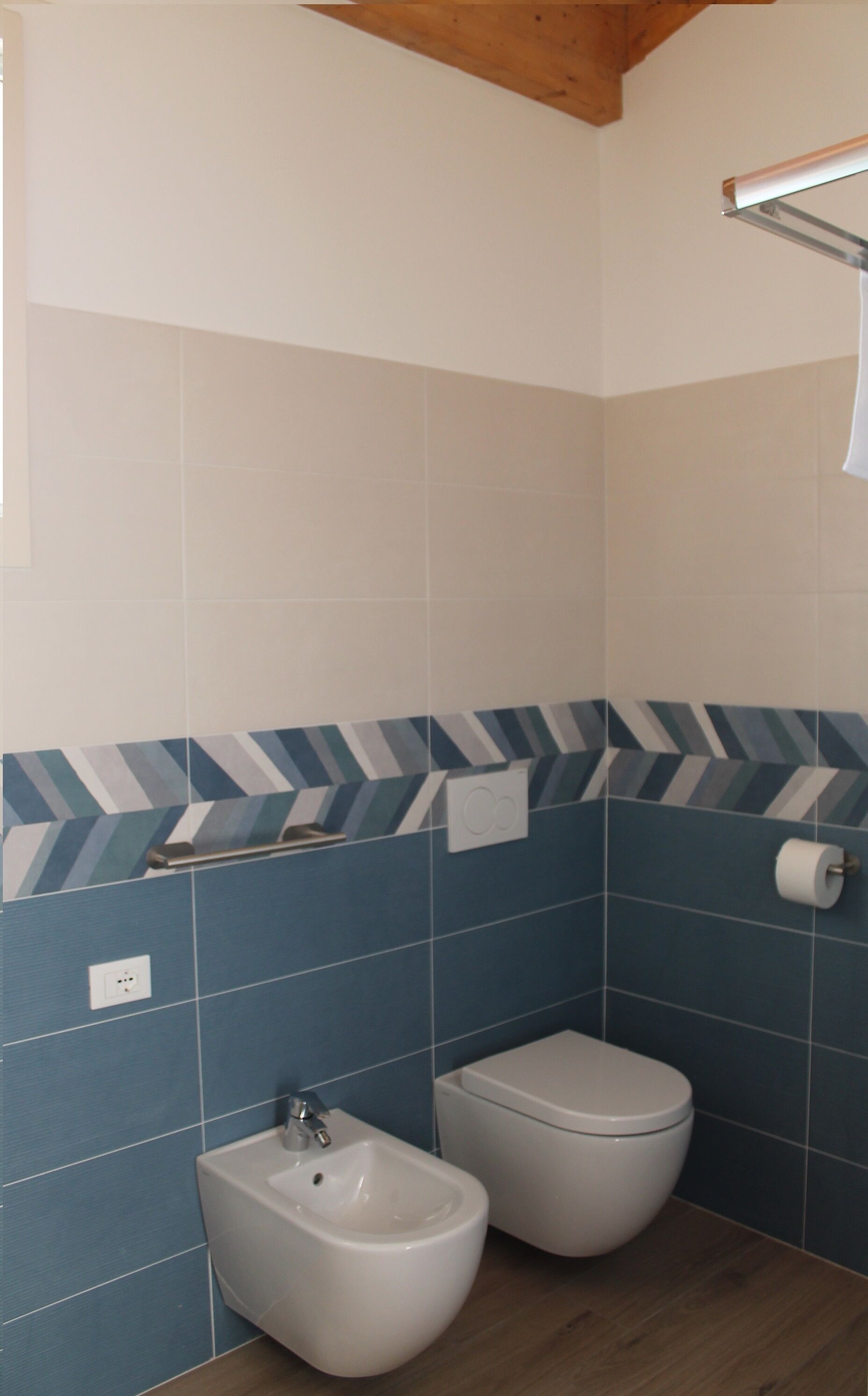 Un bagno con bidet, toilette e porta asciugamani.