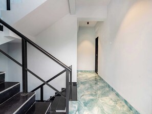 A modern interior with a staircase, a hallway with a marble floor, and a door at the end. - Palette Ventara Escape Bunglow Pvt Pool (Lonavala)