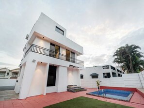 A modern two-story house with a balcony, a swimming pool, and a well-maintained lawn. - Palette Ventara Escape Bunglow Pvt Pool (Lonavala)